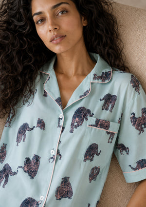 
                  
                    Woman wearing a light blue pajama top with elephant pattern
                  
                