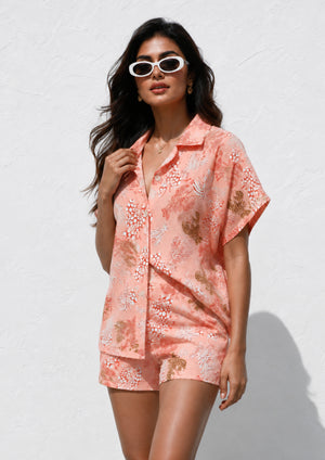 
                  
                    Woman wearing a pink floral dress against a white background
                  
                