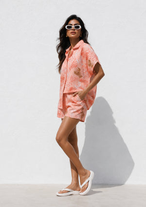 
                  
                    Woman wearing a pink floral outfit against a white background
                  
                