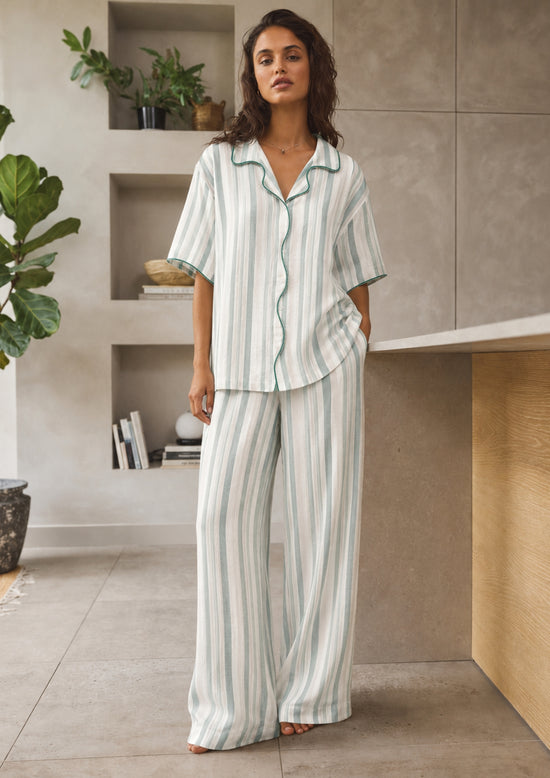 Woman wearing a striped pajama set in a modern kitchen.