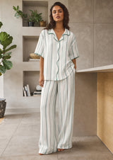 Woman wearing a striped pajama set in a modern kitchen.