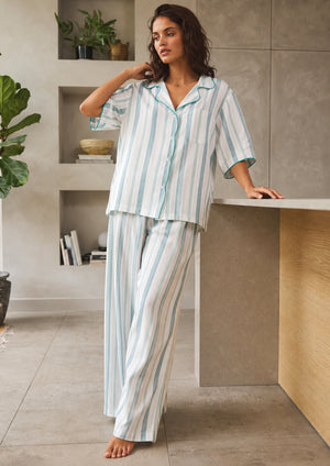 
                  
                    Woman wearing a striped pajama set in a modern interior setting.
                  
                