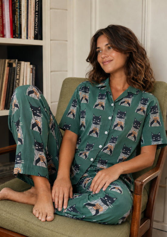 Woman with cat pajamas sitting on a chair.